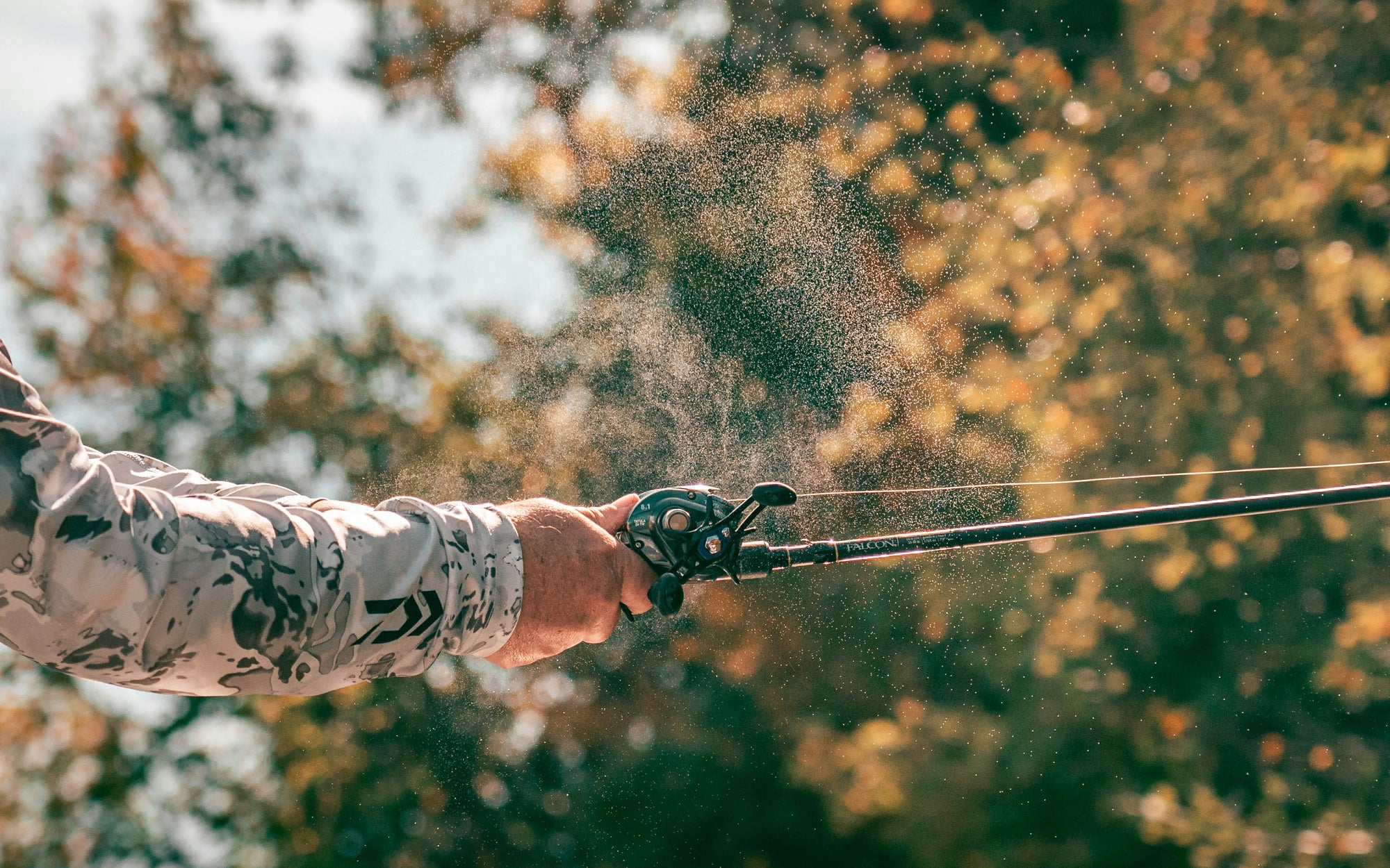 Man holding fishing rod with water particles flying